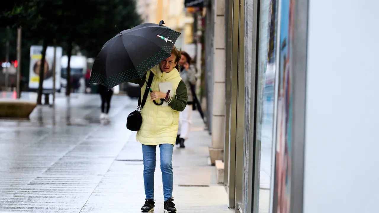 Una persona se cubre de la lluvia y el viento con paraguas. / Juanma Serrano