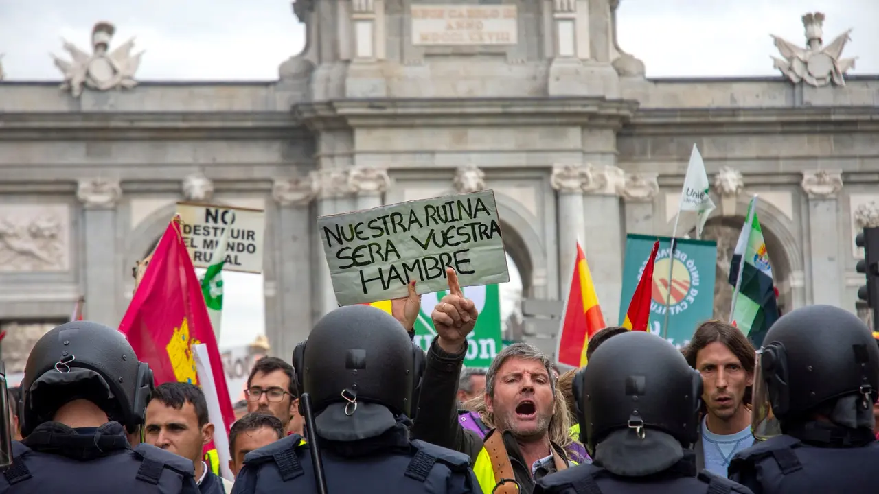 "Esta ha sido la foto elegida de Richard Zubelzu". Una captura potente que refleja la tensi&oacute;n y el clamor en las calles de Madrid durante una manifestaci&oacute;n en defensa del mundo rural. La imagen muestra a un hombre alzando un cartel con el lema "Nuestra ruina ser&aacute; vuestra hambre", mientras se enfrenta a la polic&iacute;a, en un momento de gran emotividad y protesta por la situaci&oacute;n del campo y la despoblaci&oacute;n.