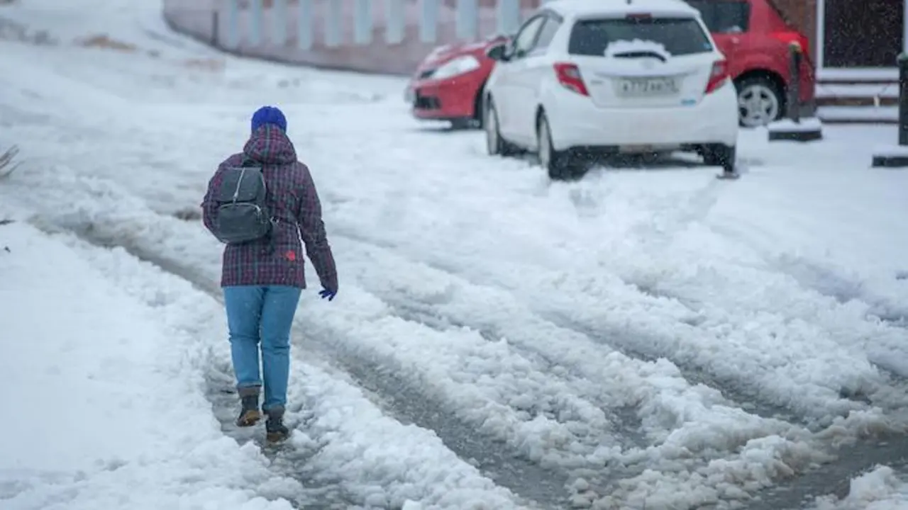 Una persona camina por una calle con niebe. / A.E
