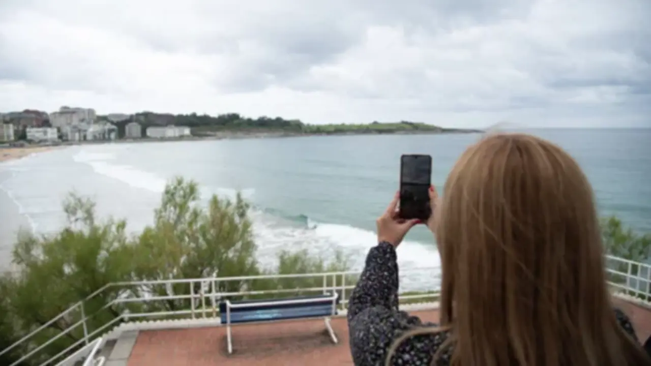 Una mujer de espaldas con su m&oacute;vil enfocando al mar. / A.E.