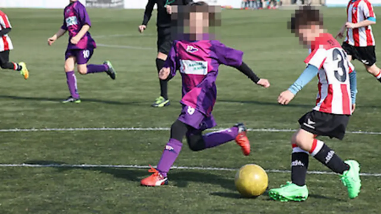 Ni&ntilde;os y ni&ntilde;as disputan un partido de f&uacute;tbol base en un ambiente de competici&oacute;n y compa&ntilde;erismo. La seguridad y el respeto en el deporte infantil son fundamentales para su desarrollo.