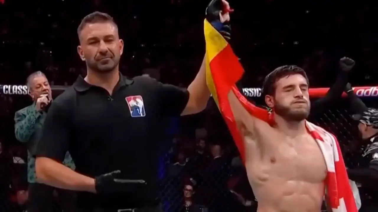 Aleksandre Topuria celebra su victoria en su debut en la UFC, con el &aacute;rbitro levantando su brazo en se&ntilde;al de triunfo. Envuelto en la bandera de Espa&ntilde;a y Georgia, el hispano-georgiano se impone por decisi&oacute;n un&aacute;nime en UFC 312, marcando el inicio de su camino en la &eacute;lite de las artes marciales mixtas.