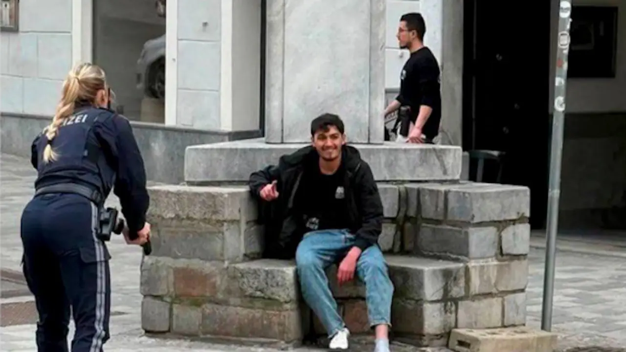 Momento de la detenci&oacute;n: agentes de polic&iacute;a apuntan con sus armas a un hombre sentado en una fuente, instantes antes de su arresto en Villach, Austria