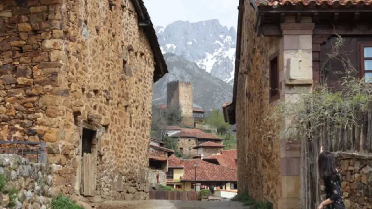 Calle empedrada de Mogrovejo, un pintoresco pueblo medieval en Cantabria, donde las antiguas casas de piedra y la imponente torre del siglo XIII se fundan con el paisaje