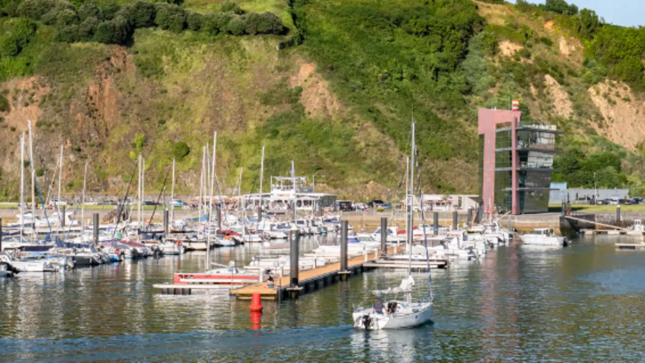 Velero entrando al puerto deportivo de Laredo con el edificio de la Marina al fondo y la monta&ntilde;a de la Atalaya. / A.S.