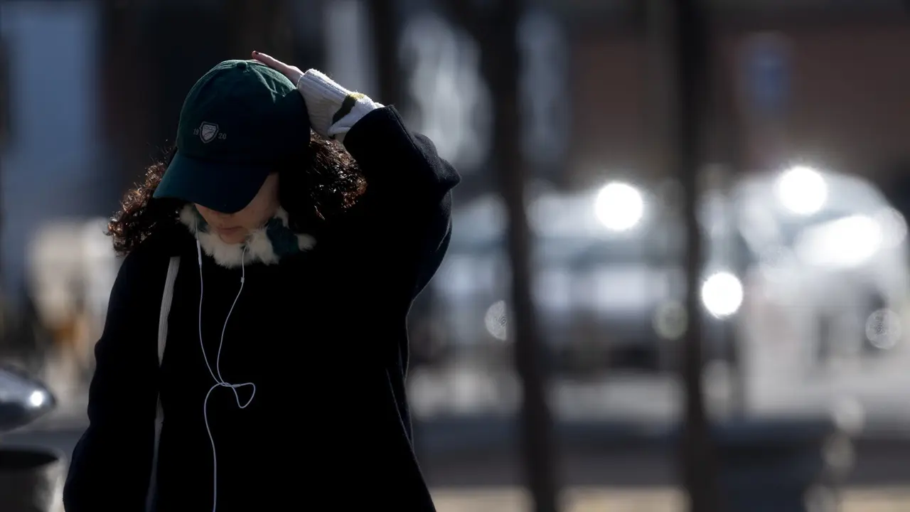 Una mujer abrigada con bufanda y gorro pasea por Madrid. / Eduardo Parra