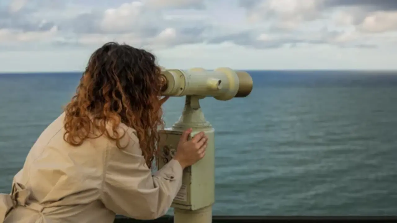 Turista usando binoculares en el Palacio de la Magdalena con vistas a la bah&iacute;a de Santander.