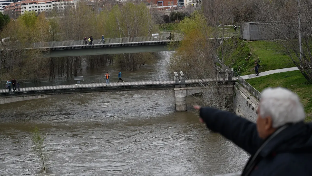Una persona observa la crecida del r&iacute;o Manzanares, en el parque de Madrid R&iacute;o. / Fernando S&aacute;nchez