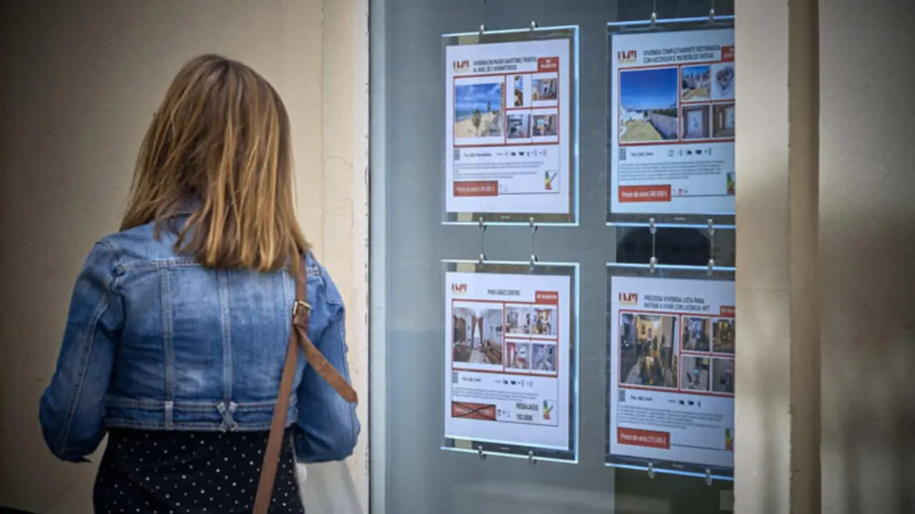 Una mujer pasa delante de una agencia inmobiliaria. / x