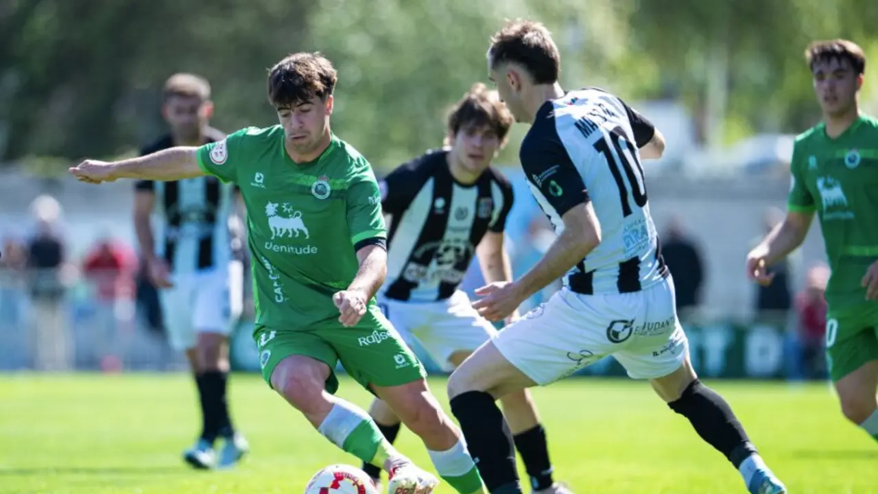 Un jugador del Rayo Cantabria protege el bal&oacute;n ante la presi&oacute;n de un rival del Escobedo durante el intenso derbi c&aacute;ntabro disputado en La Planchada.