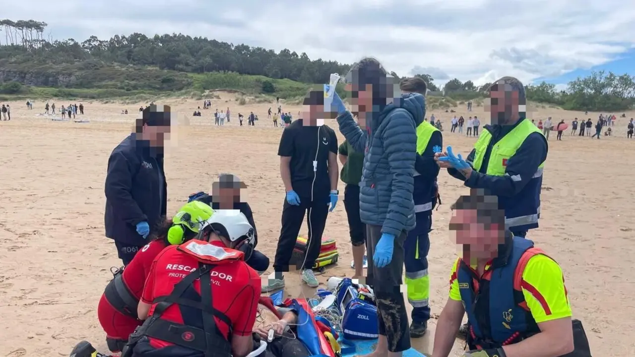 Sanitarios y rescatadores atienden en la playa de Somo a un hombre de unos 60 a&ntilde;os en estado muy grave tras ser sacado del agua por surfistas. / 112 Cantabria