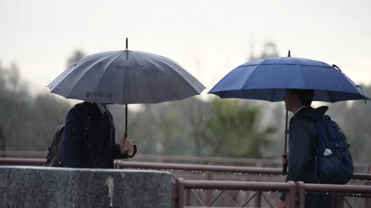 Varias personas se protegen de la lluvia con un paraguas. / Joaquin Corchero