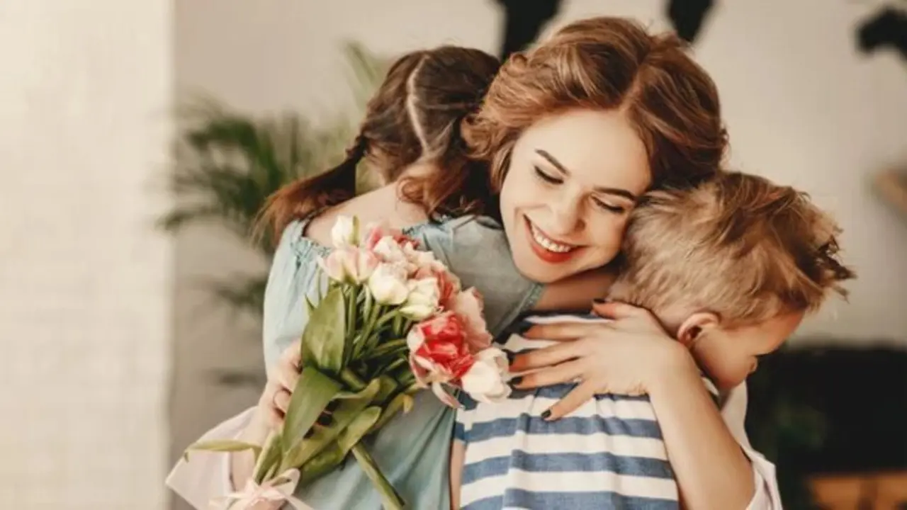 Una madre abraza a sus hijos tras entregarle un ramo de flores. / A.S.