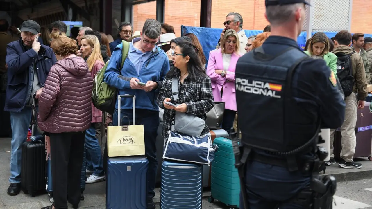 Un agente de Polic&iacute;a Nacional frente a varias personas en la estaci&oacute;n de Atocha. / EP