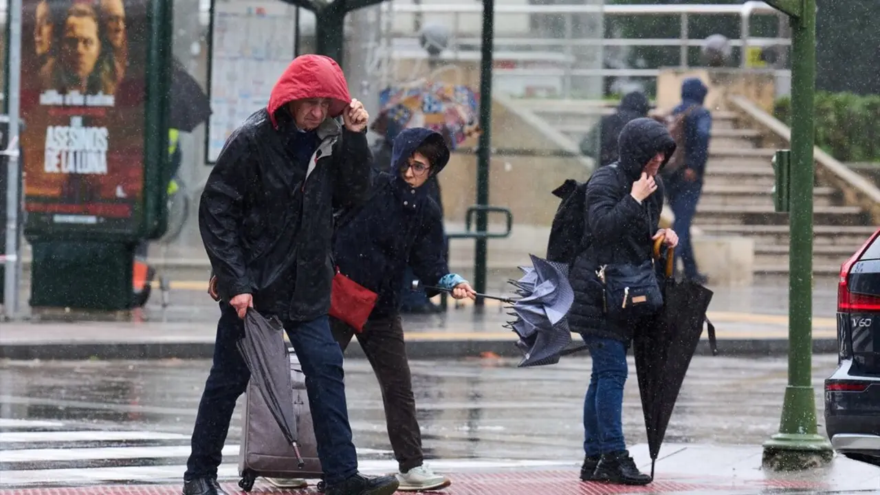Varias personas tratan de cubrirse de la lluvia y el viento. / Juanma Serrano