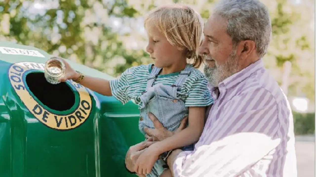 Un ni&ntilde;o junto a su abuelo tirando un tarro de vidrio en el contenedor de vidrio. / ALERTA