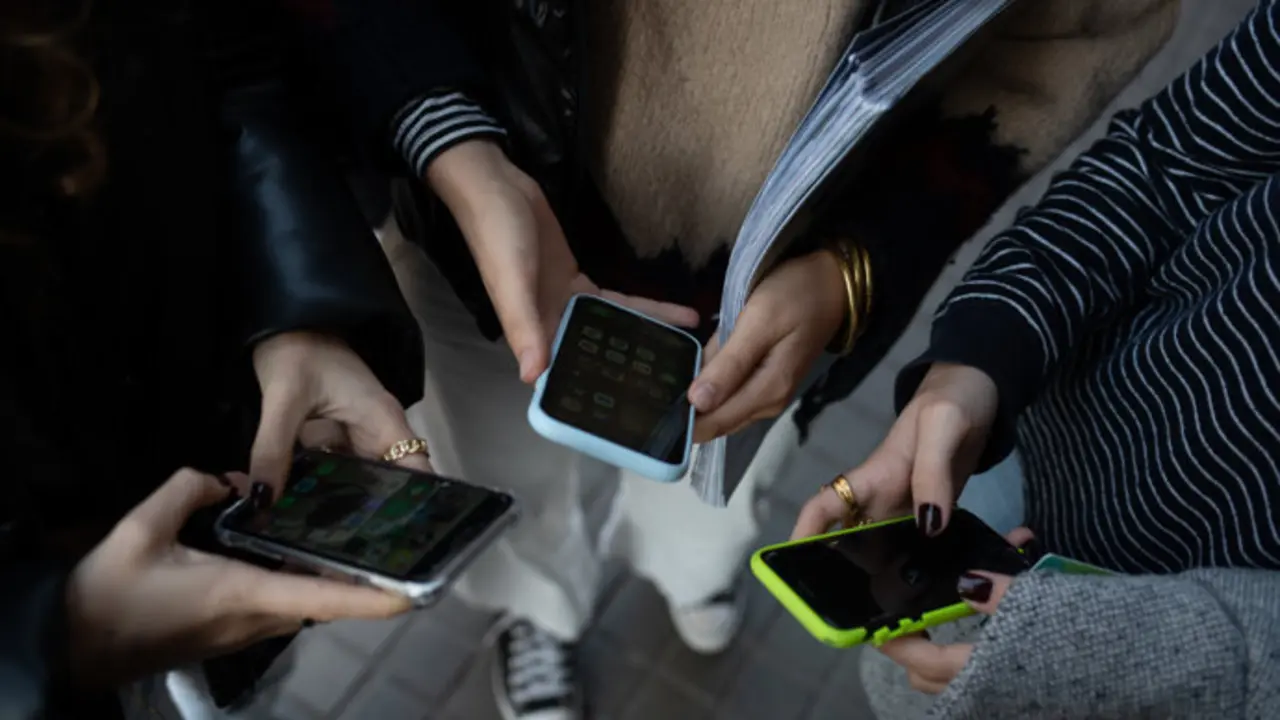 Varios ni&ntilde;os con sus m&oacute;viles en las inmediaciones del centro escolar. / EP