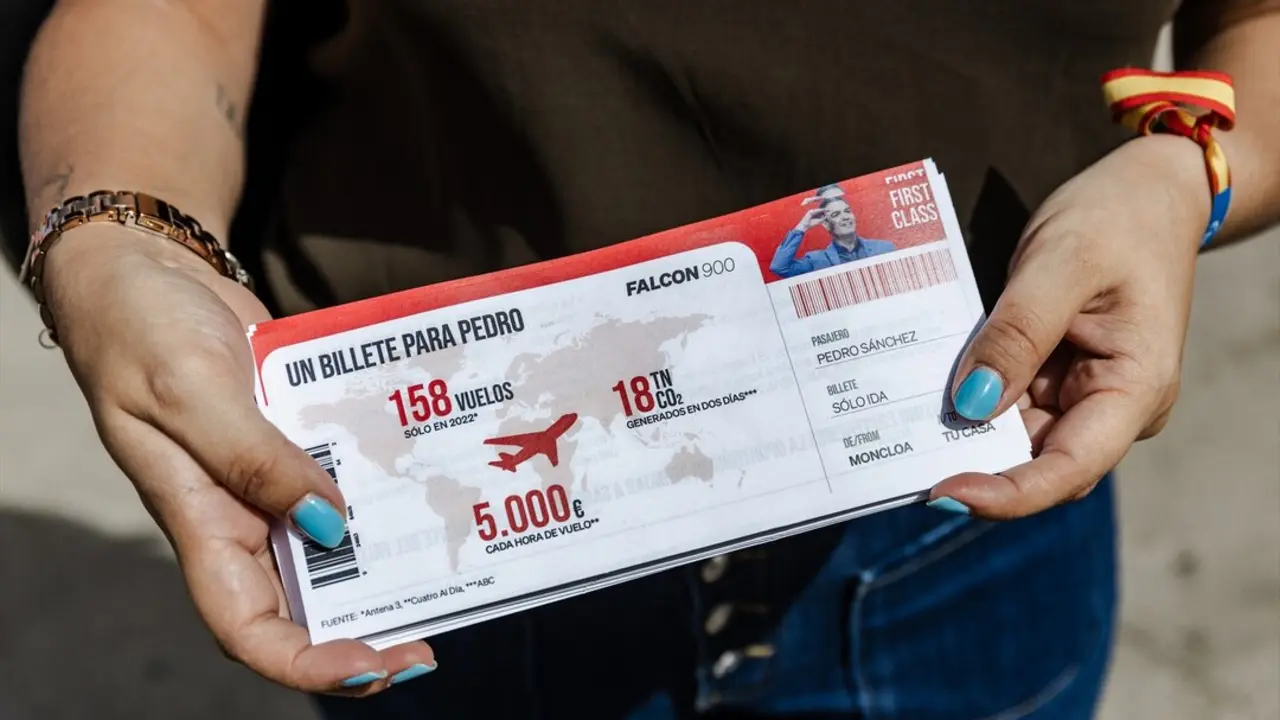 Una persona muestra el billete de avi&oacute;n que se entrega en la maqueta del avi&oacute;n Falcon 900 en la calle Recoletos. / Carlos Luj&aacute;n / Archivo