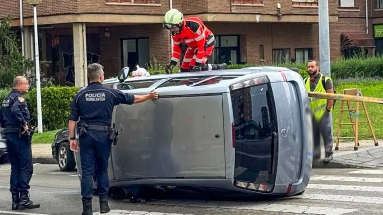 Polic&iacute;as tratan de rescatar a la conductora del veh&iacute;culo volcado, este martes, en El Zapat&oacute;n (Torrelavega).