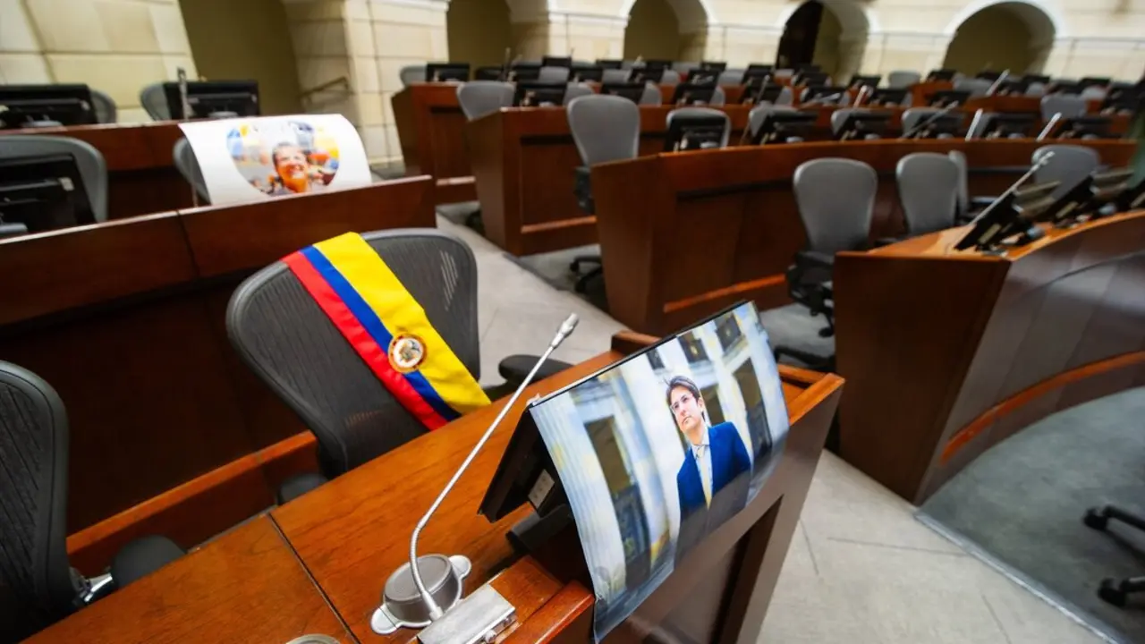 Fotograf&iacute;as y una banda de la bandera de Miguel Uribe Turbay reposan en su silla dentro del Capitolio. / EP