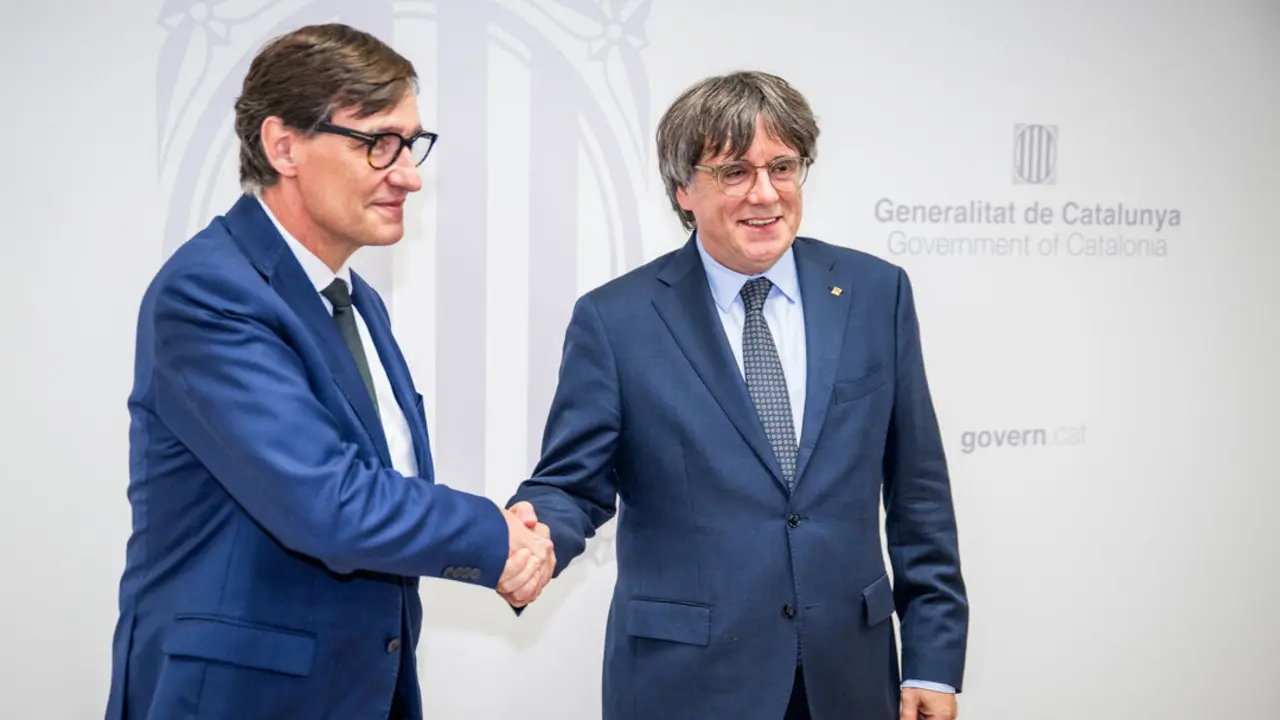 El presidente de la Generalitat, Salvador Illa (i), saluda al presidente de Junts per Catalunya, Carles Puigdemont. / EP
