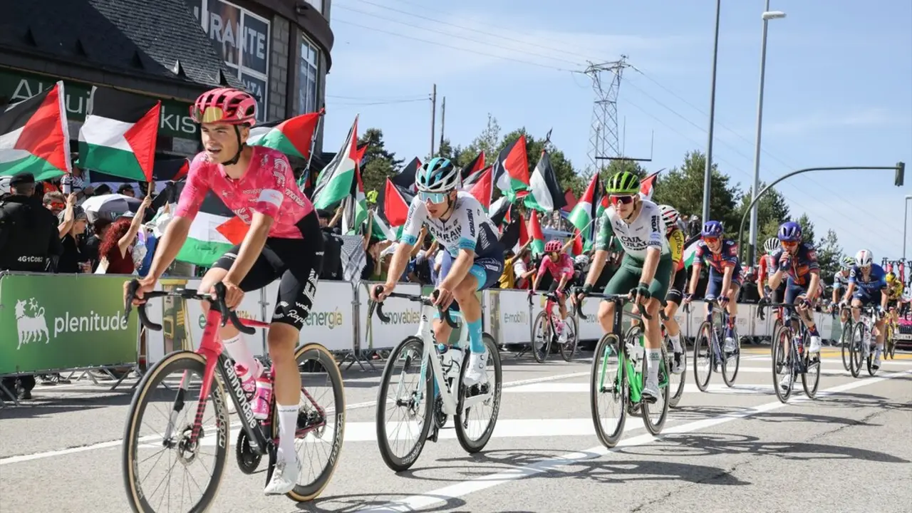 Varios ciclistas pasan por una zona con protestas propalestinas durante la 20&ordf; etapa de la Vuelta Ciclista a Espa&ntilde;a. / Rafael Bastante