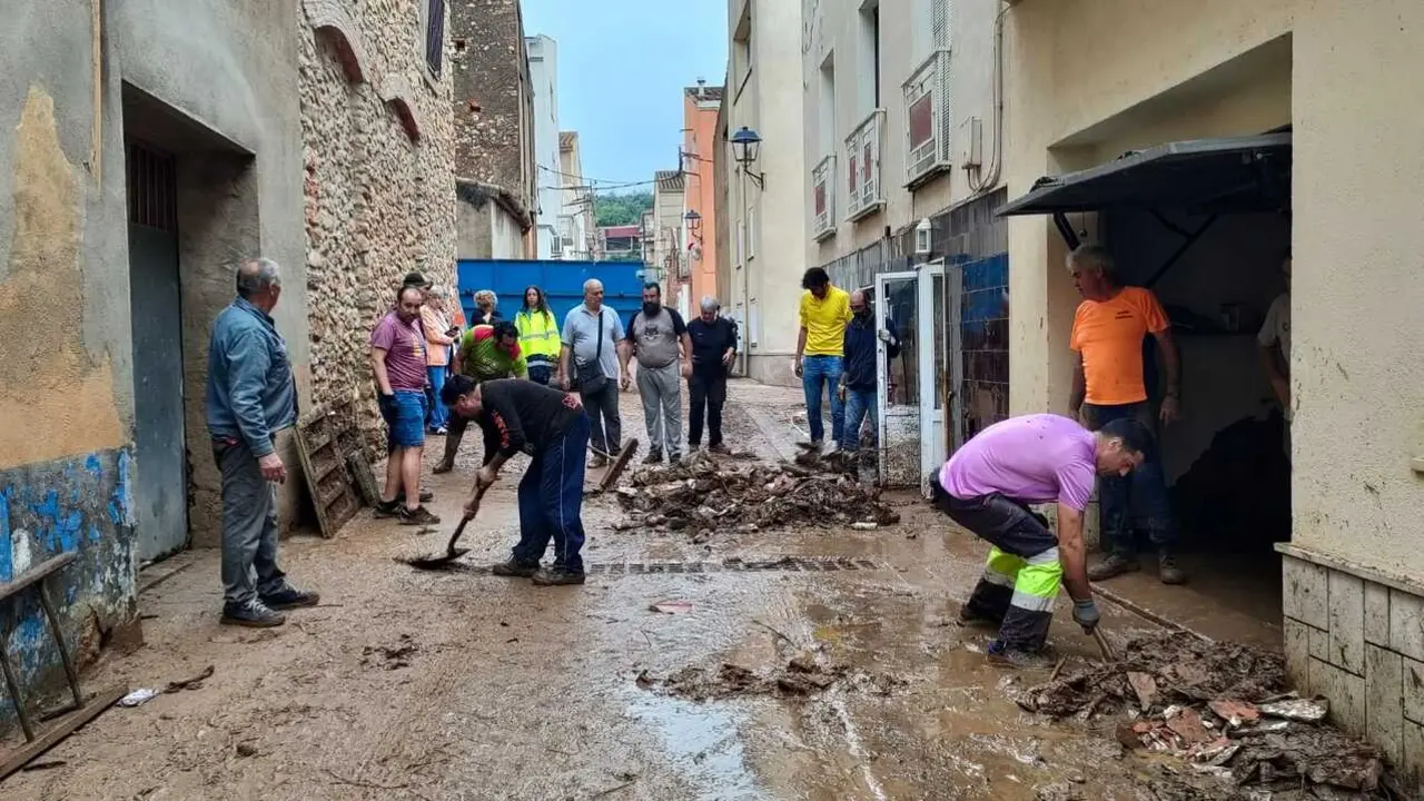 Afectaciones en una de las calles del municipio, donde los vecinos limpian y retiran los restos de lodo. / EP