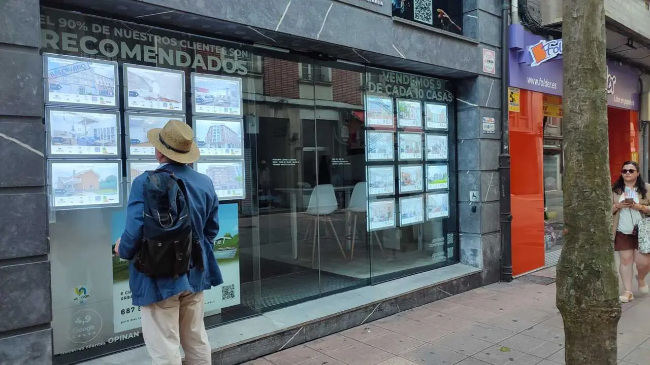 Un hombre mira varios anuncios en el escaparate de una agencia inmobiliaria. / EP