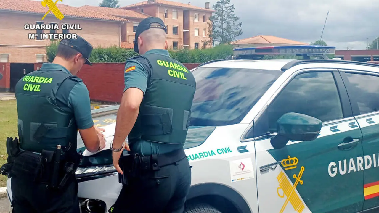 Dos guardias civiles junto al coche patrulla. / G.C.