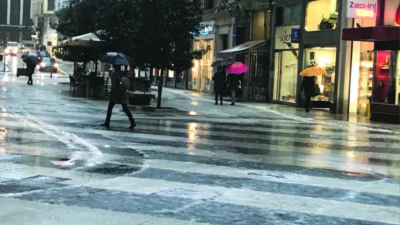 Varias personas con paraguas pasean bajo la lluvia en el centro de Santander. / alerta