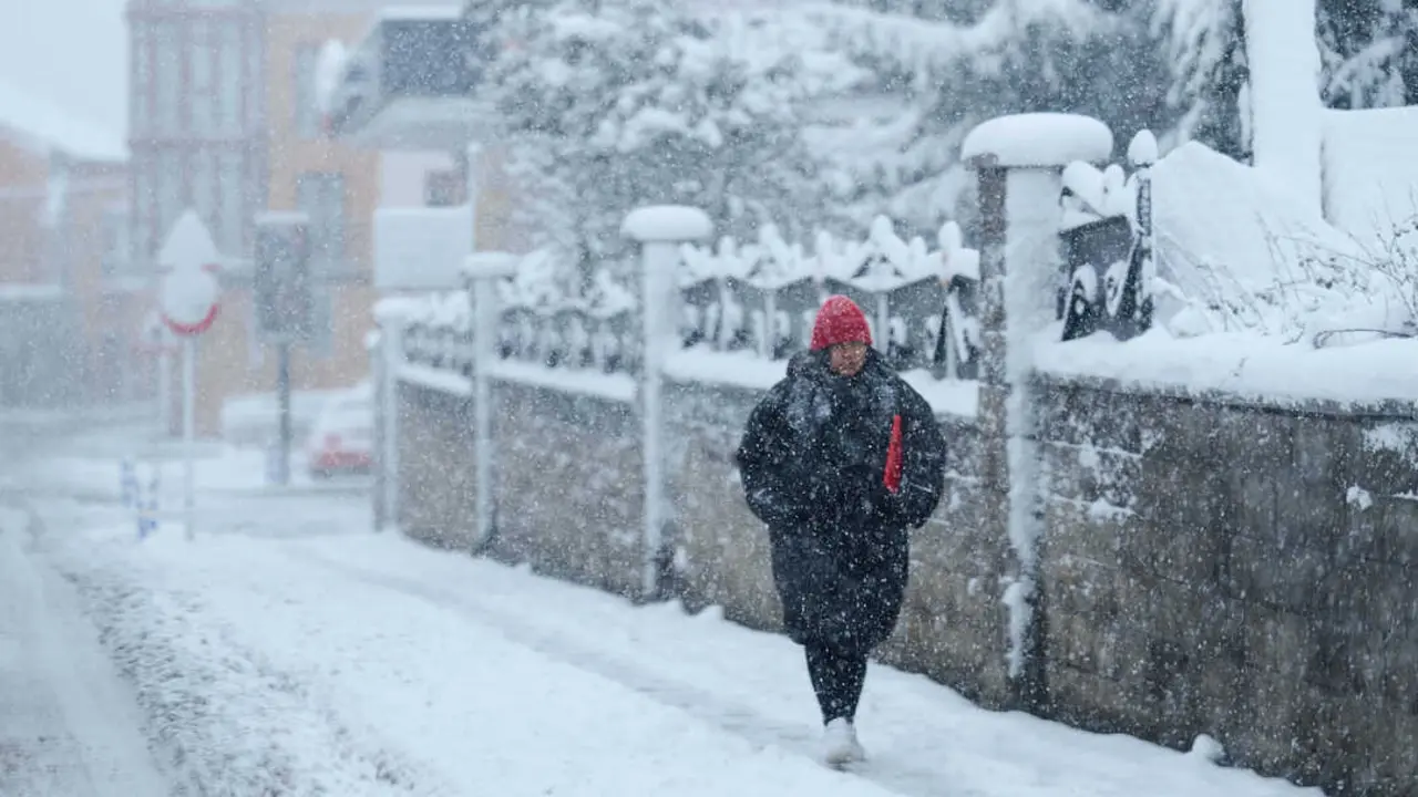 Una mujer camina por la calle mientras nieva. / EP