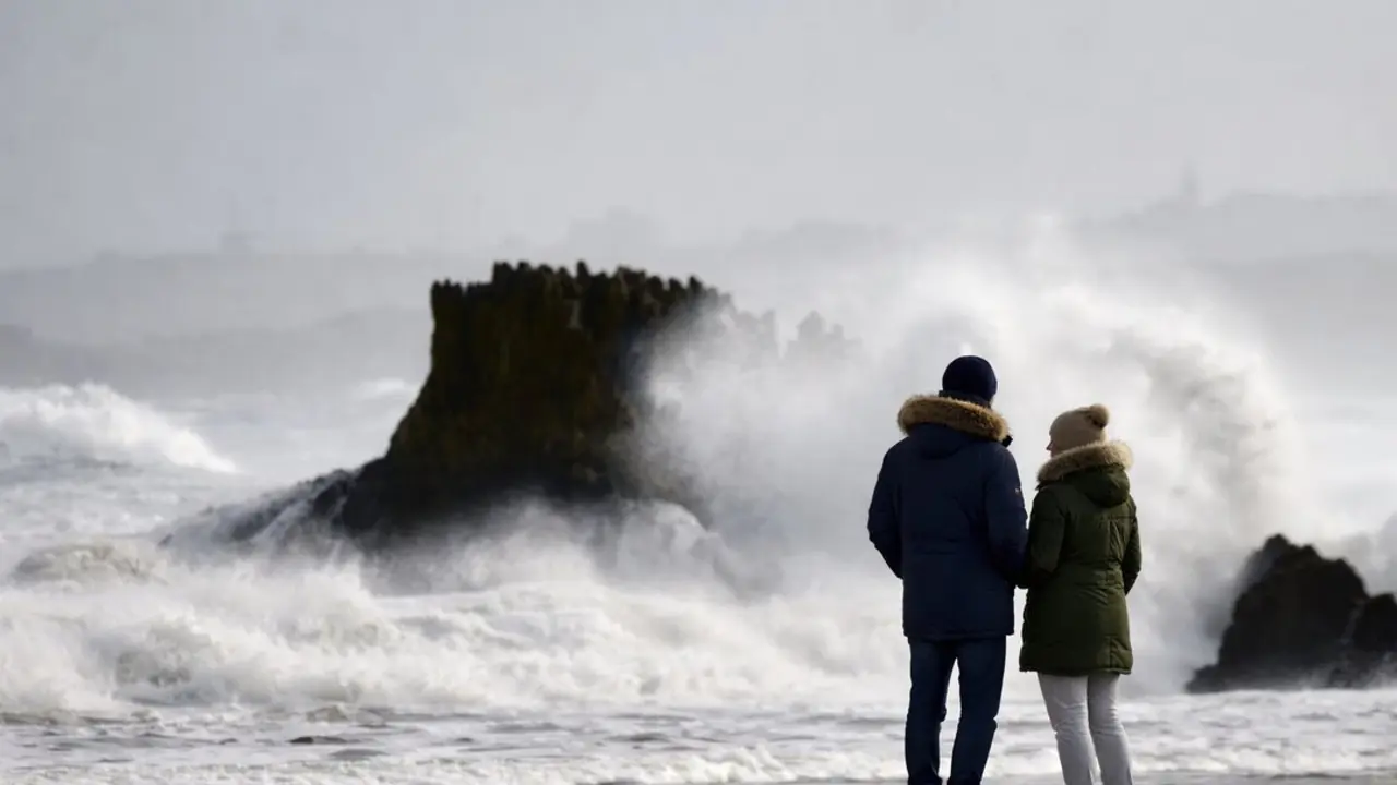 Una pareja contempla el bravo oleaje del mar Cant&aacute;brico en Santander, mientras las olas rompen con fuerza contra las rocas en un d&iacute;a de temporal invernal. / ALERTA