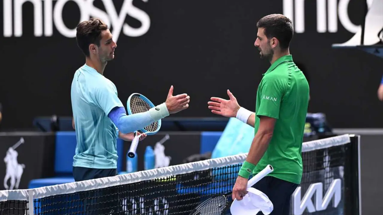 Novak Djokovic saluda en la red a Lorenzo Mussetti tras el abandono del italiano en los cuartos de final del Abierto de Australia 2026. / Joel Carrett