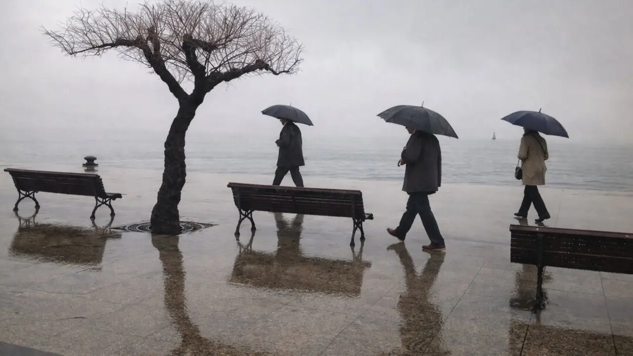 Varias personas por el Paseo Pereda de Santander, frente a la bah&iacute;a de la ciudad.