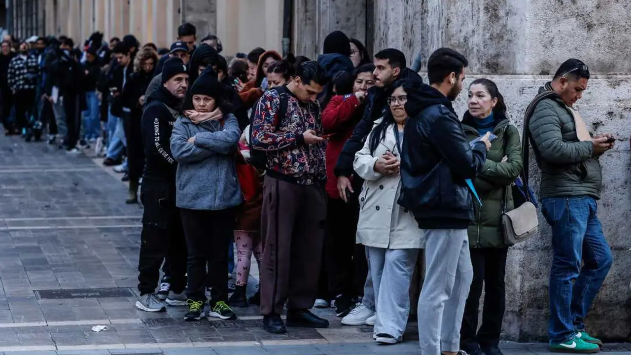 Decenas de inmigrantes hacen cola en el Ayuntamiento de Valencia. / EP