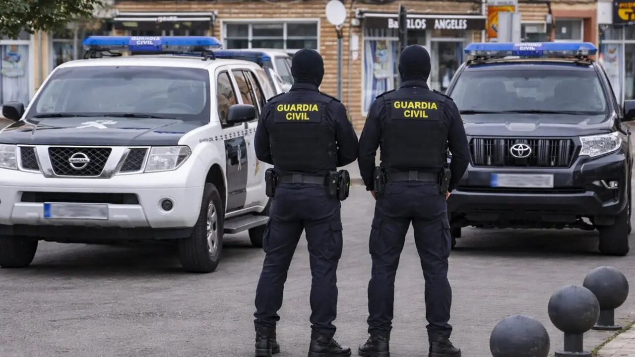 Dos agentes de la Guardia Civil junto a veh&iacute;culos oficiales durante el operativo desplegado en Cantabria que se ha saldado con doce detenidos por tr&aacute;fico de drogas.