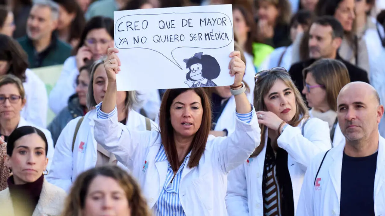 Una mujer, vestida con bata m&eacute;dica, sostiene un cartel durante una concentraci&oacute;n de sanitarios. En el mensaje puede leerse: &ldquo;Creo que de mayor ya no quiero ser m&eacute;dica&rdquo;, acompa&ntilde;ado de una ilustraci&oacute;n, reflejando el malestar del colectivo. A su alrededor, decenas de profesionales de la salud participan en la protesta, evidenciando el clima de reivindicaci&oacute;n en el sector sanitario. Juanma Serrano - Europa Press - Archivo