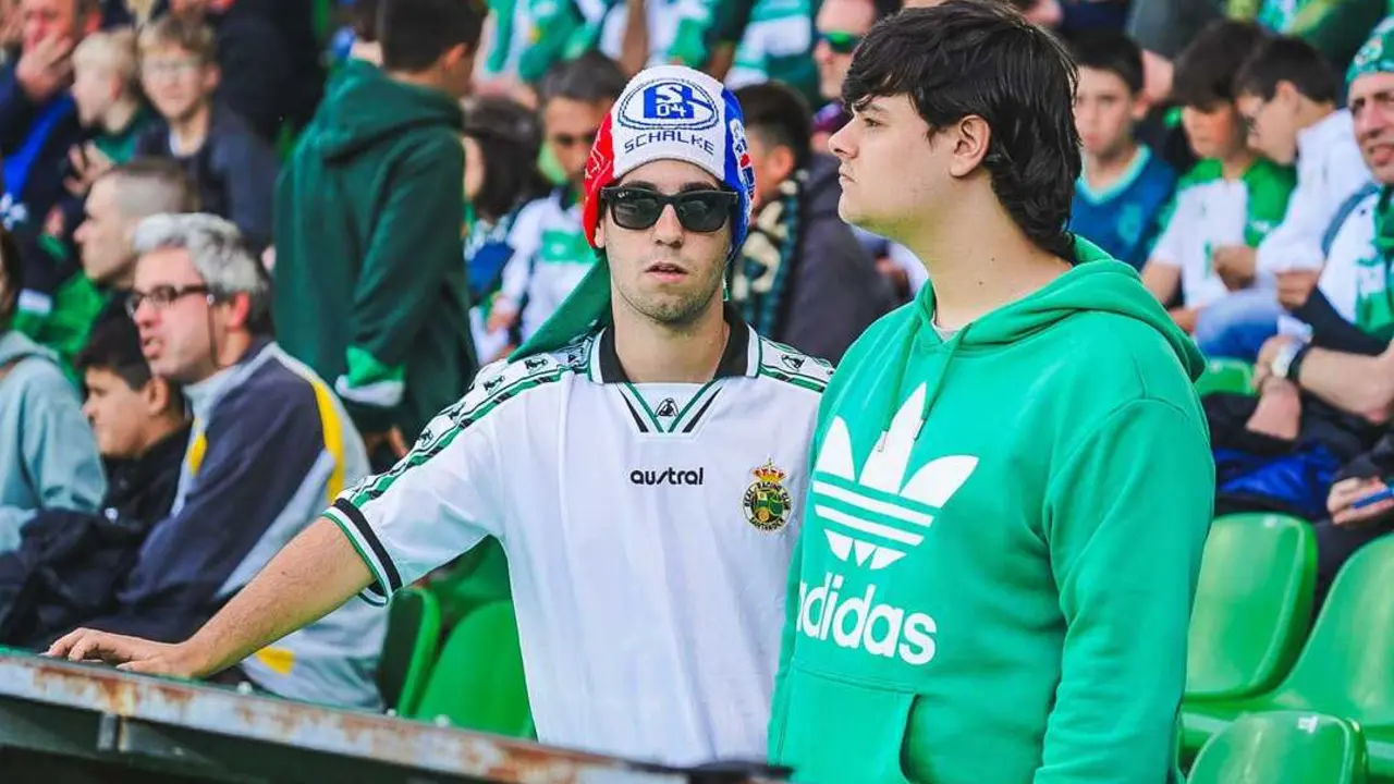 Dos aficionados del Racing esperan el inicio del partido en El Sardinero, uno de ellos con un llamativo gorro del Schalke 04 en una grada completamente entregada a la ilusi&oacute;n del ascenso.