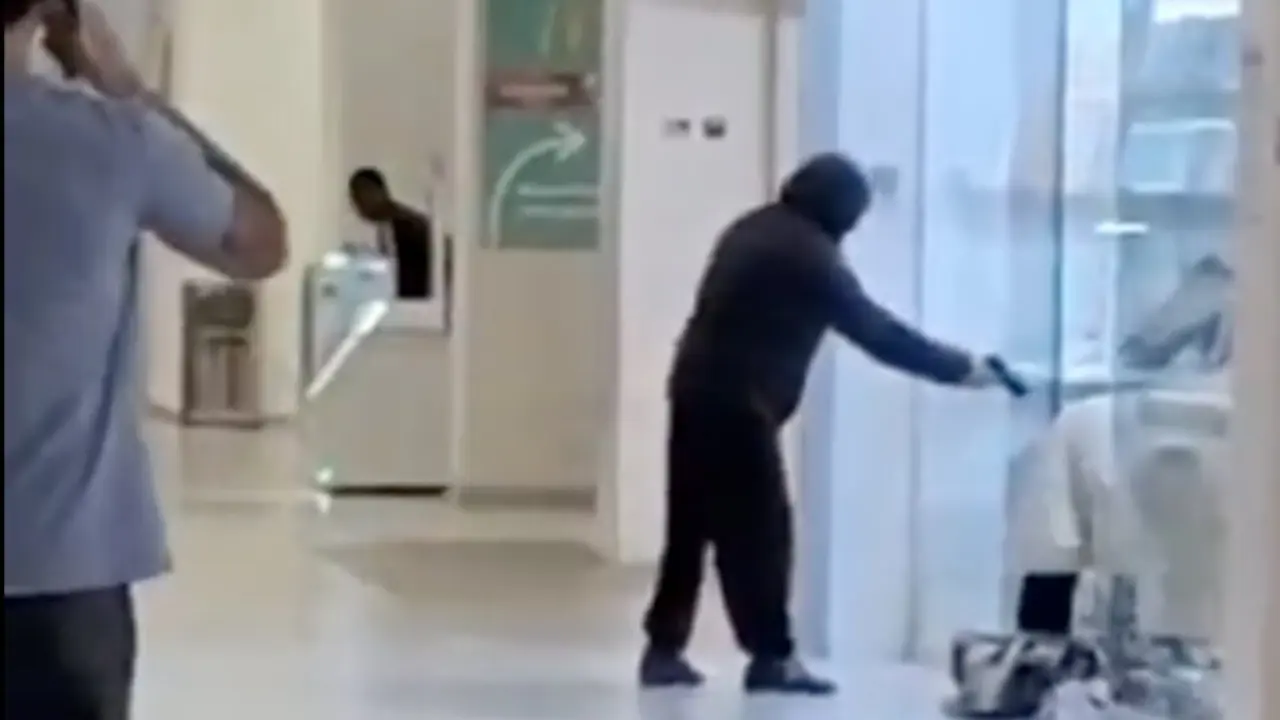 Instante del violento atraco a la joyer&iacute;a del centro comercial Madrid Sur, en Puente de Vallecas, donde uno de los encapuchados amenaza a una trabajadora mientras sus compinches destrozaban las vitrinas para llevarse las joyas.