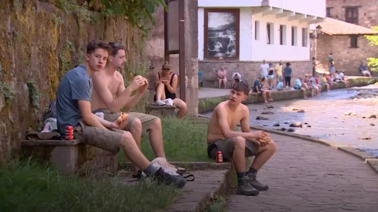 Varias personas descansan junto al r&iacute;o en Potes para combatir las altas temperaturas durante la jornada de alerta roja por calor en la comarca de Li&eacute;bana.