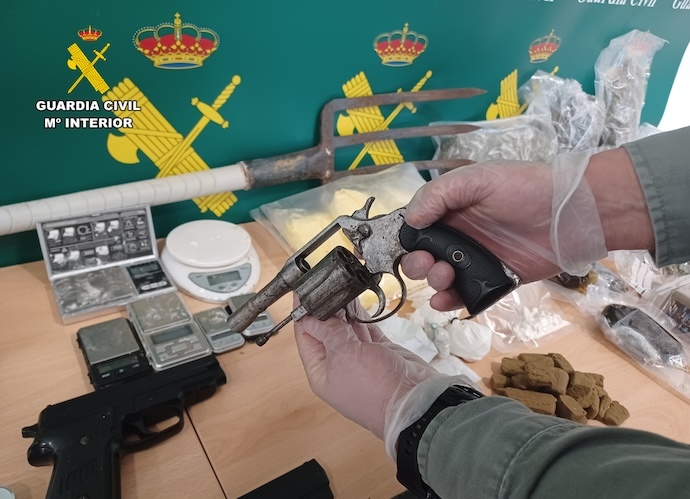 Revolver y pistolas simuladas intervenidas junto a balanzas y utensilios utilizados para el tráfico de estupefacientes.