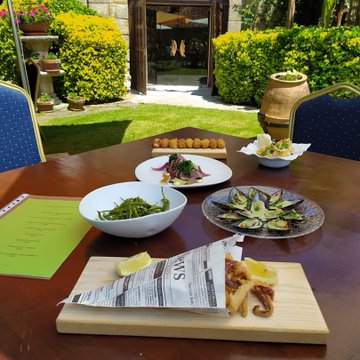 Un festín de sabores en un entorno idílico: mariscos frescos, croquetas caseras y productos de la tierra se combinan en una mesa al aire libre, perfecta para disfrutar de la gastronomía cántabra.