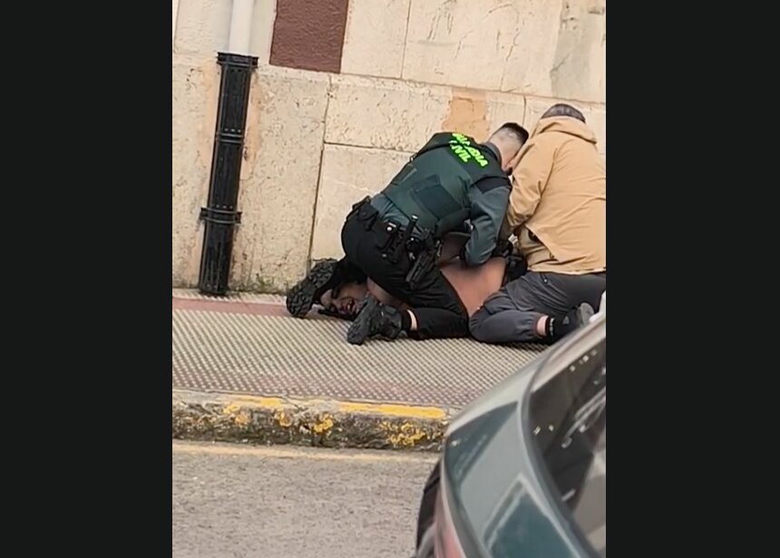 Un agente de la Guardia Civil y un vecino inmovilizan a uno de los implicados en la acera durante la intervención en Castro Urdiales.