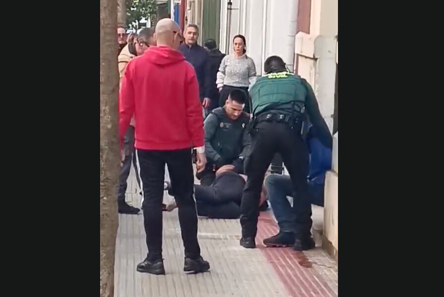 Varios vecinos observan la intervención de la Guardia Civil mientras los agentes reducen a uno de los implicados en plena calle en Castro Urdiales.