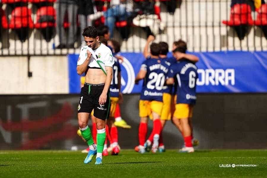 Jugadores del FC Andorra celebran uno de los goles ante un Racing superado, mientras un futbolista verdiblanco se lamenta tras el duro golpe en Encamp.