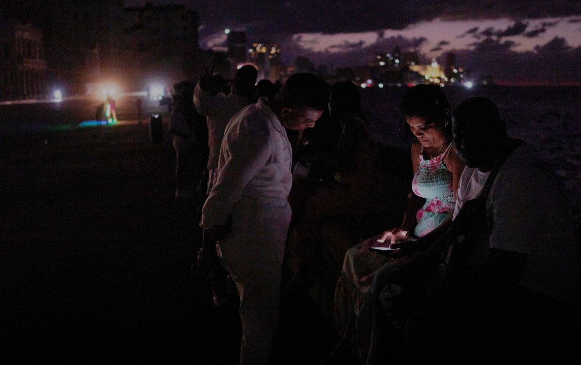 Varias personas consultan sus móviles en plena oscuridad junto al Malecón de La Habana durante uno de los continuos cortes eléctricos que sufre Cuba.